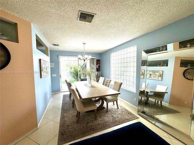 dining area featuring visible vents, a chandelier, a textured ceiling, and light tile patterned flooring