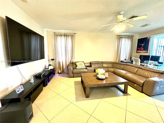 living area featuring tile patterned flooring, a textured ceiling, visible vents, and a ceiling fan