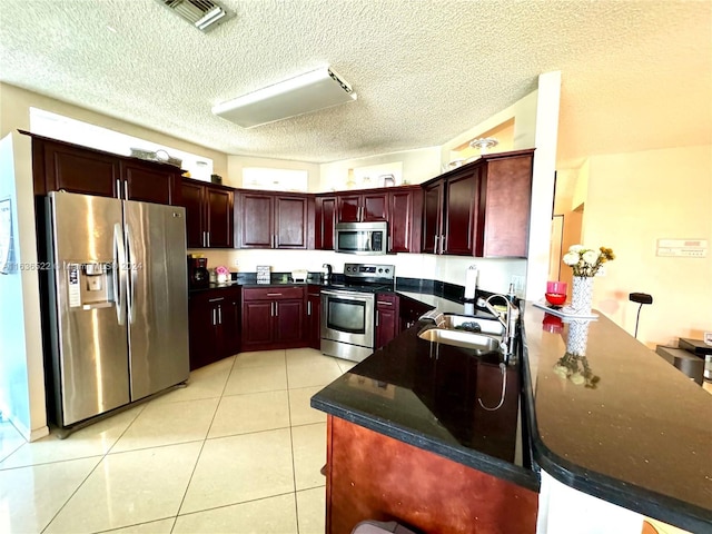 kitchen featuring visible vents, appliances with stainless steel finishes, dark brown cabinets, a sink, and light tile patterned flooring