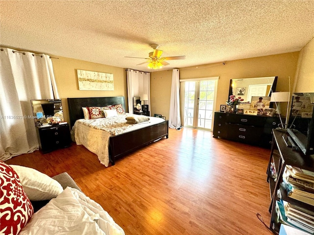 bedroom with a textured ceiling, ceiling fan, wood finished floors, access to exterior, and french doors