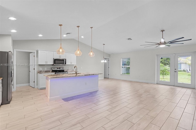 kitchen featuring sink, hanging light fixtures, stainless steel appliances, light stone counters, and white cabinets