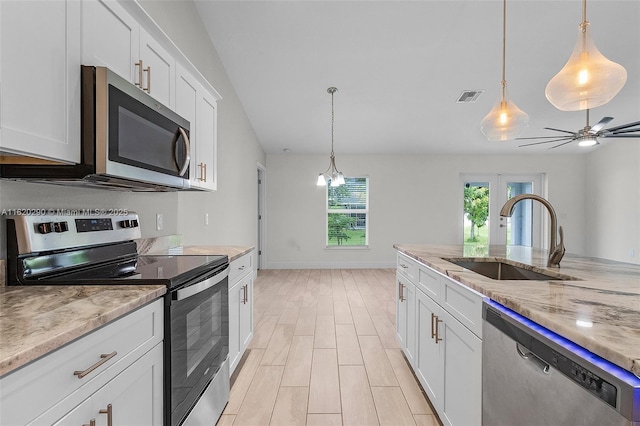 kitchen featuring sink, white cabinets, hanging light fixtures, and appliances with stainless steel finishes