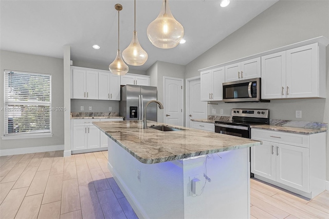 kitchen with appliances with stainless steel finishes, sink, a center island with sink, white cabinetry, and hanging light fixtures