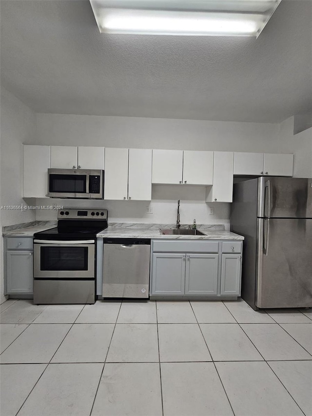 kitchen featuring appliances with stainless steel finishes, light tile patterned floors, sink, and gray cabinetry