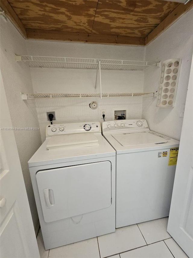 laundry area with washing machine and clothes dryer, light tile patterned floors, and wood ceiling