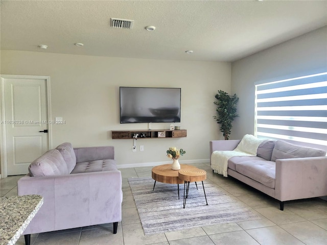 living room with a textured ceiling and light tile patterned floors