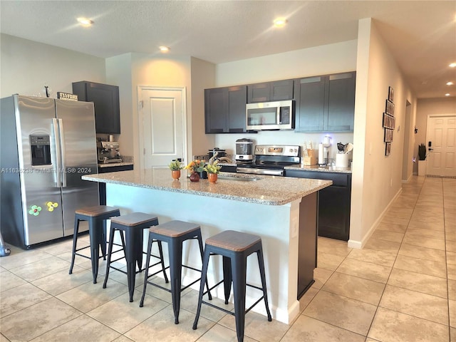 kitchen with a kitchen island, appliances with stainless steel finishes, and a kitchen breakfast bar