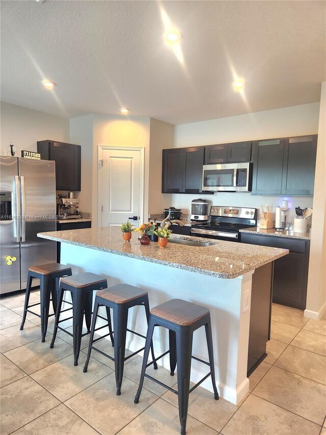 kitchen with sink, appliances with stainless steel finishes, a center island with sink, and a breakfast bar