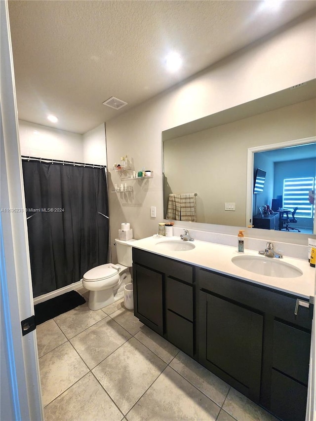 bathroom featuring toilet, a textured ceiling, tile patterned flooring, and double vanity