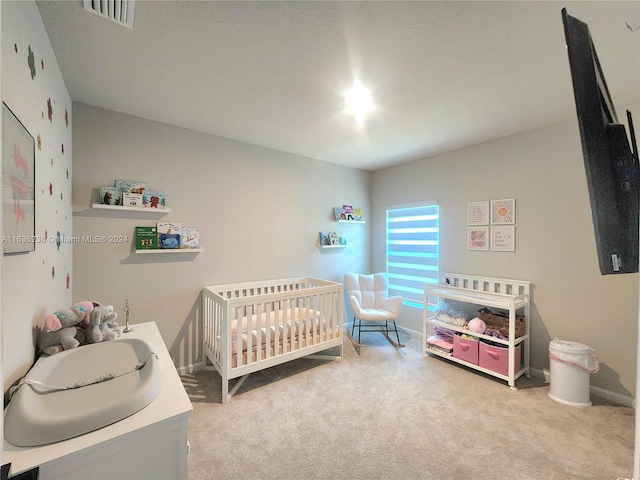 bedroom with carpet floors, a textured ceiling, and a nursery area