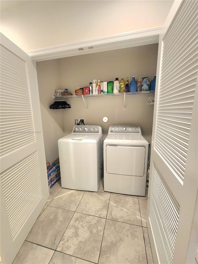 laundry area with washing machine and clothes dryer and light tile patterned floors