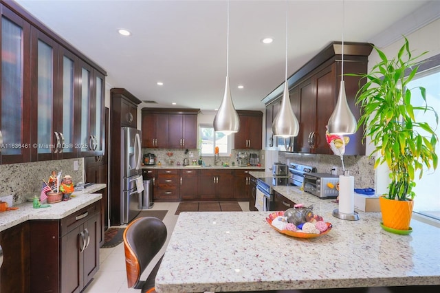 kitchen with appliances with stainless steel finishes, a sink, decorative backsplash, and light stone countertops