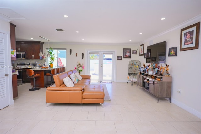 tiled living room with crown molding and french doors