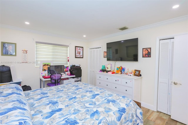 bedroom with light wood-type flooring, visible vents, ornamental molding, and two closets