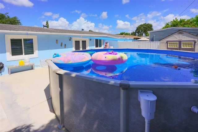 outdoor pool with french doors, fence, and a patio