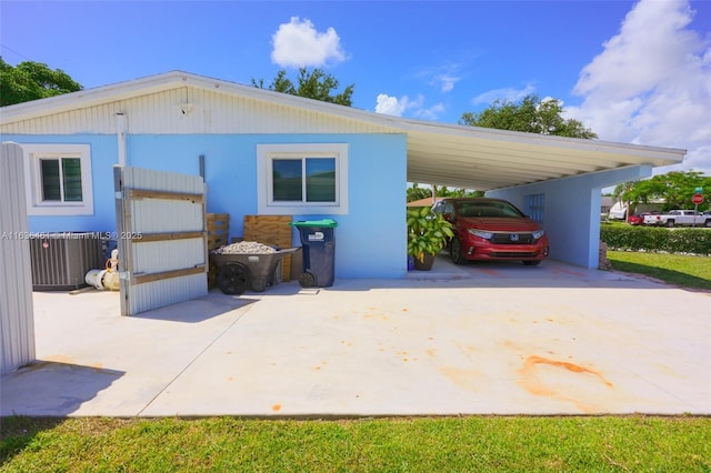 exterior space with central AC, an attached carport, and driveway