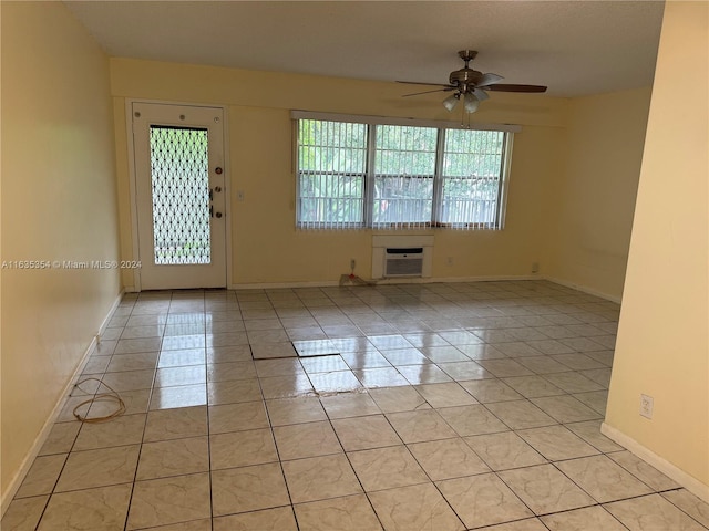 unfurnished room featuring a wall unit AC, ceiling fan, baseboards, and light tile patterned flooring