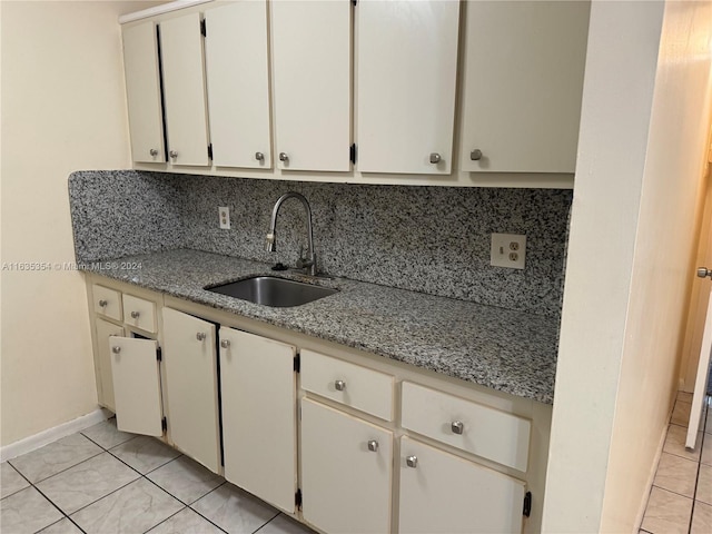 kitchen with light tile patterned floors, baseboards, backsplash, and a sink