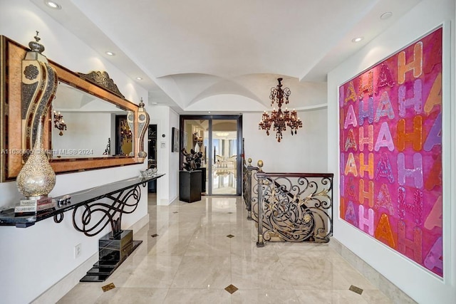 hallway with tile patterned flooring and a chandelier