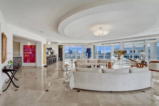 living room featuring floor to ceiling windows, a tray ceiling, and light tile patterned floors