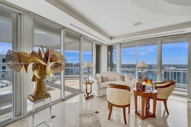 sunroom with a raised ceiling, a water view, and plenty of natural light