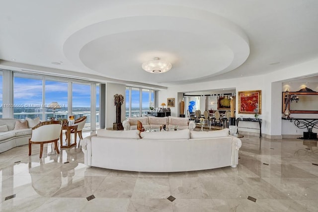 living room with light tile patterned flooring, floor to ceiling windows, and a tray ceiling