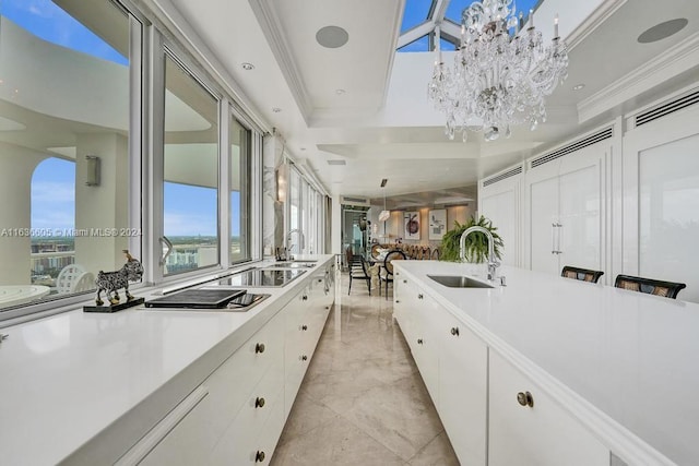 kitchen featuring white cabinetry, a notable chandelier, light tile patterned floors, a raised ceiling, and sink