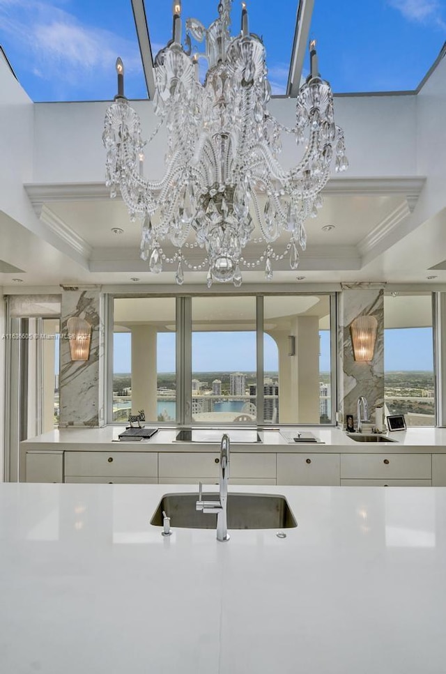 kitchen with an inviting chandelier, sink, and a raised ceiling