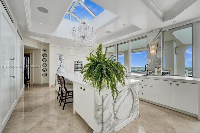 kitchen with an inviting chandelier, white cabinetry, a raised ceiling, and light tile patterned floors