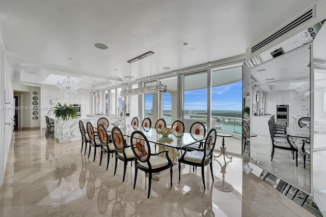 tiled dining area with a water view, sink, and an inviting chandelier