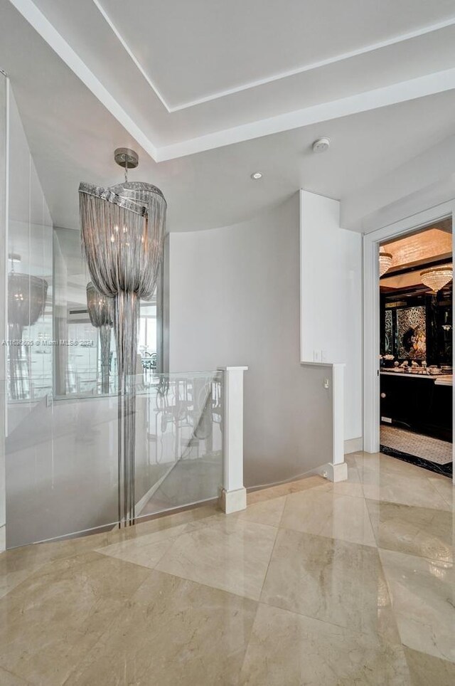 interior space featuring a raised ceiling, a notable chandelier, and light tile patterned floors