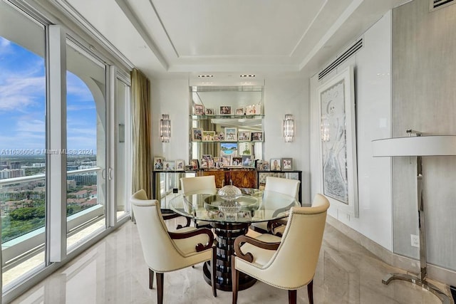 dining space featuring light tile patterned flooring and a raised ceiling