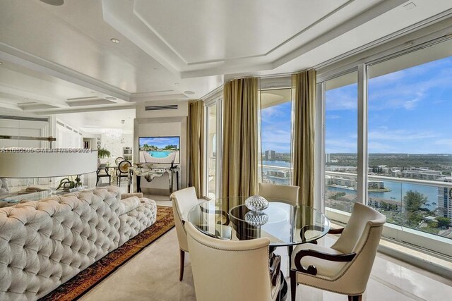 dining space with a raised ceiling, a water view, and plenty of natural light