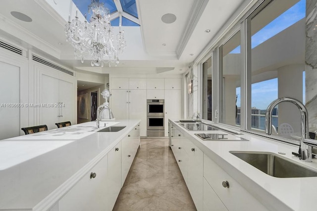 kitchen with sink, light tile patterned flooring, white cabinets, and a raised ceiling