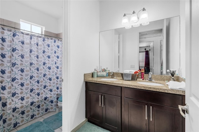 bathroom featuring tile patterned flooring, dual vanity, and toilet