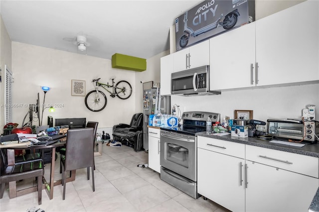 kitchen with stainless steel appliances, light tile patterned floors, and white cabinets