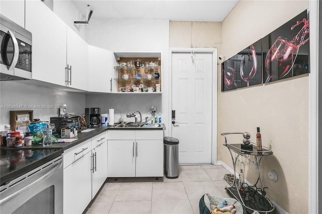 kitchen featuring sink, range with electric stovetop, light tile patterned floors, and white cabinets