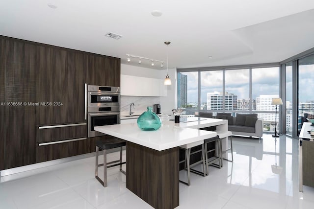 kitchen with stainless steel double oven, a wealth of natural light, light tile patterned floors, and track lighting