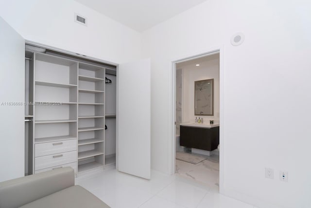 unfurnished bedroom featuring a closet, ensuite bath, visible vents, and baseboards