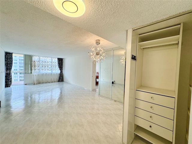 interior space with light tile patterned floors, a wall of windows, a chandelier, and a textured ceiling