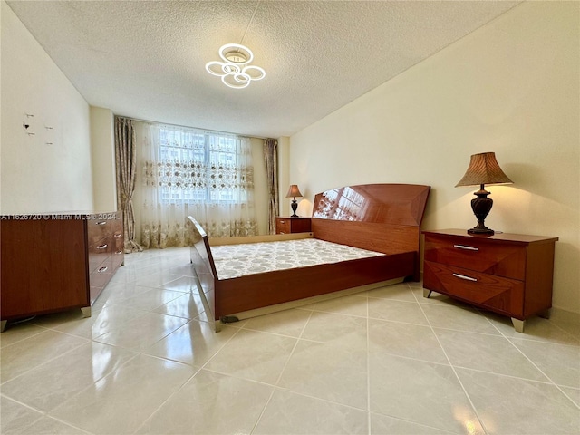 bedroom with light tile patterned flooring, expansive windows, and a textured ceiling