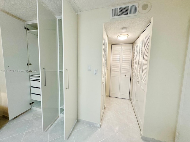 hallway with light tile patterned floors and a textured ceiling