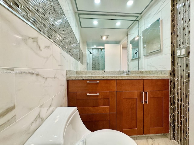 bathroom with tile walls, toilet, and vanity