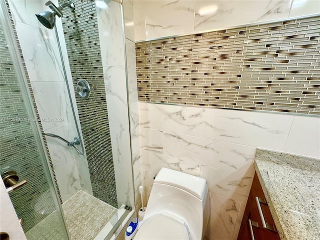 bathroom with tile walls, toilet, vanity, and an enclosed shower