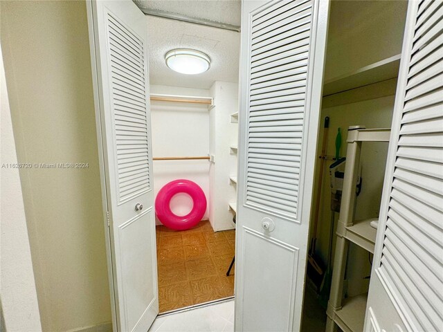 clothes washing area featuring light tile patterned flooring and a textured ceiling