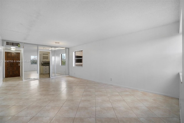 empty room with light tile patterned floors and a textured ceiling