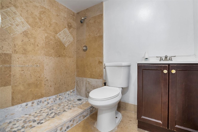 bathroom with toilet, a tile shower, vanity, and tile patterned floors