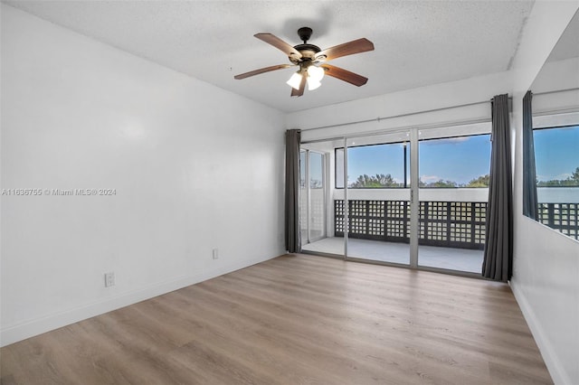 empty room with ceiling fan, wood-type flooring, and a textured ceiling