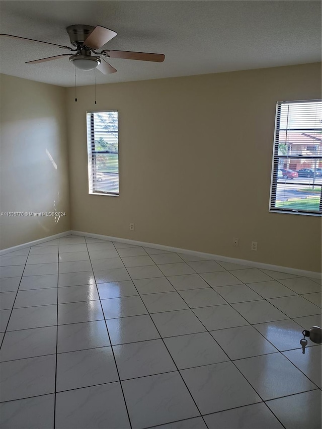 empty room with light tile patterned flooring, ceiling fan, and plenty of natural light