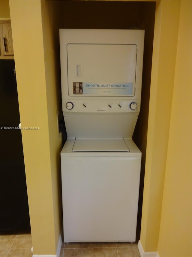 washroom with stacked washing maching and dryer and light tile patterned flooring